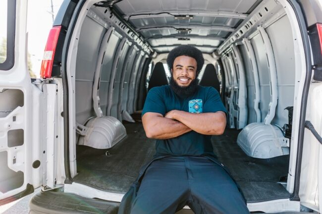Person sitting inside a cargo van, illustrating interior space affected by wheelbase and roof height.